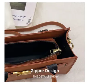Dettaglio borsa vintage marrone con cerniera liscia e fibbia a cuore in metallo dorato
