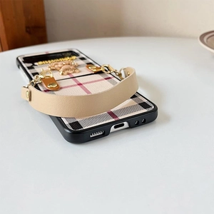 Detail of checkered foldable phone case for Samsung Z Flip with bear charm and leather strap