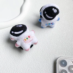 Detail of plush astronaut phone socket stands in pink and blue on textured surface