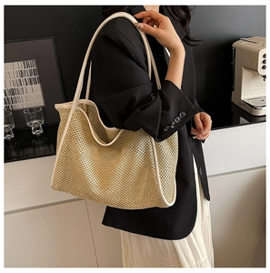 Detailed close-up of woven straw texture and white leather handles on a large tote bag