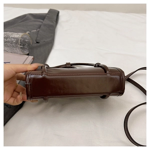 Detailed close-up of chocolate brown PU leather crossbody bag with FASHION lettering
