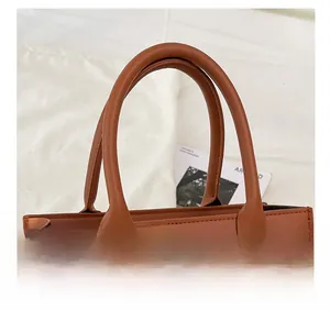 Dettaglio dei manici ergonomici e finiture dorate su borsa tote in ecopelle marrone