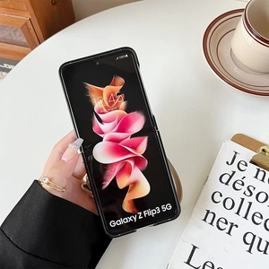 Detail of a chic black Samsung Z Flip case held by hand in a lifestyle office setting