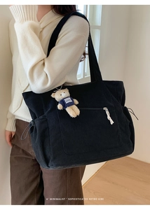 Detail of black corduroy tote bag featuring a zipper pocket and a cute bear plush keychain