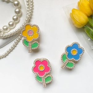 Détail de supports téléphone en forme de fleurs avec pétales colorés et perles nacrées