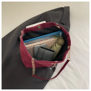 Spacious interior of burgundy suede tote bag with chain strap holding daily essentials
