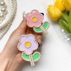 Détail du support téléphone fleur avec pétales roses, perles blanches et fini émaillé