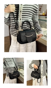 Detail of black crossbody bag with crocodile embossing and golden crescent buckle clasp