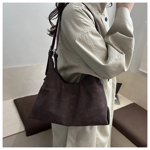 Detail of a dark brown suede tote bag on a beige trench coat for a minimalist office look