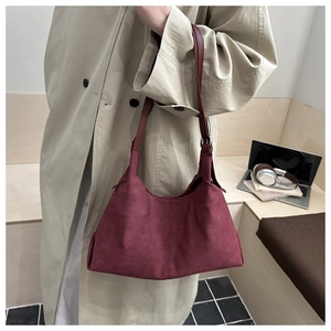Deep red suede tote bag shown on model with adjustable strap for a stylish commuter look