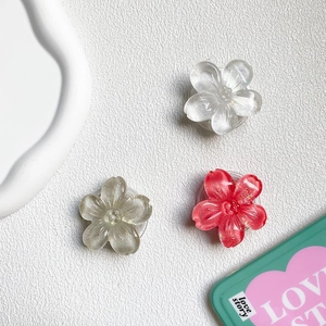 Detailed view of 3D resin flower phone grips in clear, champagne gold, and red finishes