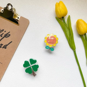 Detail view of flower and clover phone grip set on a wooden clipboard background