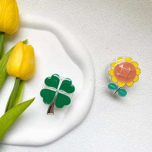 Electroplated clover and sunflower phone grip stands on a white ceramic tray