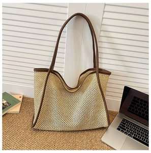 Detail of hand-woven straw tote bag with brown leather handles and large capacity