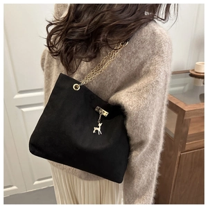 Matte black tote bag with gold chain and deer charm shown worn by a model