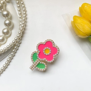Détail d'un support de téléphone en fleur avec pétales roses, feuilles vertes et perles