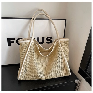 Close-up of woven straw tote bag featuring detailed mesh texture and creamy leather trim