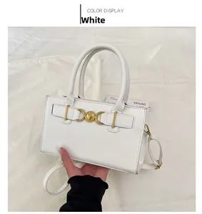 Detailed shot of a white leather handbag featuring a unique heart-shaped gold buckle