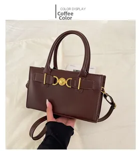 Detail view of coffee brown tote bag featuring gold heart metal buckle and twin handles