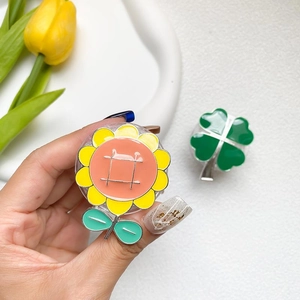 Detailed view of sunflower and clover alloy phone stands with vibrant enamel finish