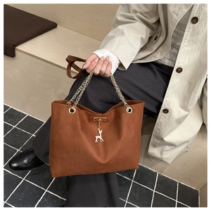 Close-up of retro brown velvet tote bag with gold chain strap and deer charm detail