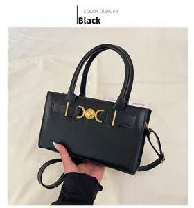 Detail of black leather handbag with a gold heart clasp and adjustable strap