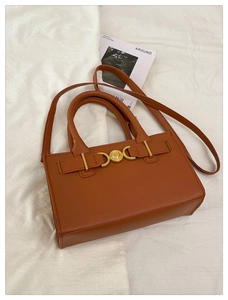 Dettaglio di una borsa marrone strutturata con fibbia a cuore dorata e tracolla coordinata