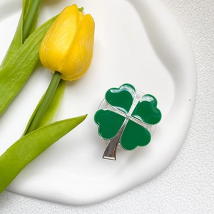 Detail shot of a green clover cell phone grip holder on a white ceramic display tray