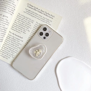 Transparent phone case with cream bear grip stand on a minimalist aesthetic background