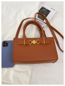 Vista dettagliata della borsa in pelle marrone con chiusura a cuore dorata e tracolla