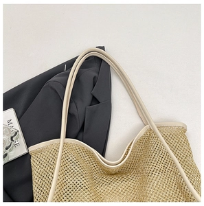Detail of woven mesh tote bag featuring golden metallic texture and cream leather handles