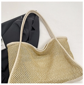 Detail of woven mesh tote bag with beige leather trim on a black blazer background