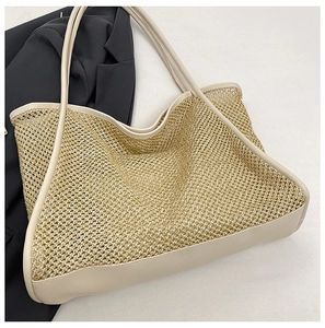 Macro detail of the beige woven straw pattern and brown leather straps of the tote bag