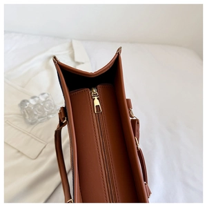 Detail shot of the brown PU leather tote bag featuring a gold metal zipper closure