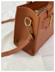 Dettaglio della borsa in pelle caramello con finiture in metallo dorato e cuciture fini