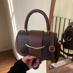 Brown woven leather handbag with gold metal bar accent and adjustable shoulder strap
