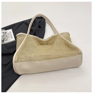 Close-up of golden hollow straw weave texture and white leather handles on large tote bag