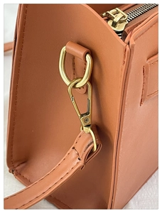 Primo piano della borsa in pelle caramello con cerniera e fibbia in metallo dorato