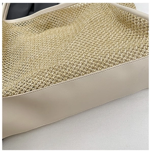 Close-up of woven raffia texture and off-white leather trim on large summer tote bag