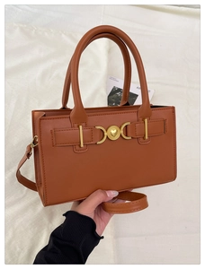 Dettaglio borsa in ecopelle caramello con fibbia a cuore dorata e cuciture rifinite