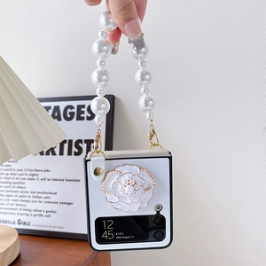 Détail de coque Samsung Z Flip avec camélia blanc, perles et bandoulière en strass