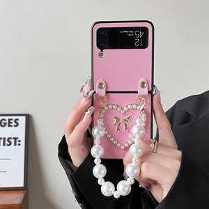Pink Z Flip case detail showing lychee texture, heart emblem, and pearl handle strap