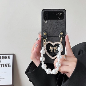 Close-up of black lychee leather phone case with pearl handle and heart bow charm