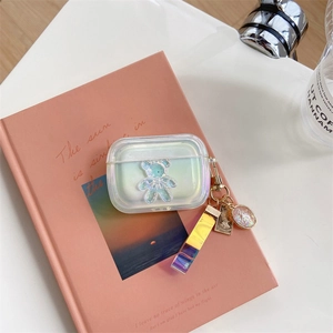 Détail d'étui AirPods Pro laser arc-en-ciel avec ours 3D et pendentif sur livre rose