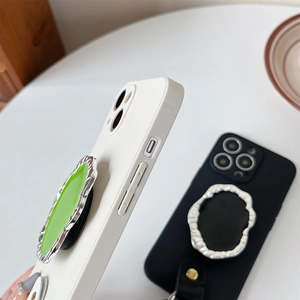 Close-up of white phone case featuring a silver wavy metallic phone socket with green core