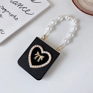Detail of black leather phone case with pearl heart, gold bow and pearl handle strap