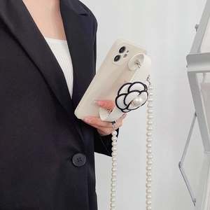 Elegant iPhone case with pearl strap and camellia wristband on minimalist cream cover