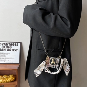 Detail of checkered folding phone case with gold bear motif and elegant chain strap