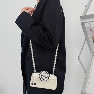 White iPhone crossbody case featuring 3D camellia flower and pearl strap worn with black suit