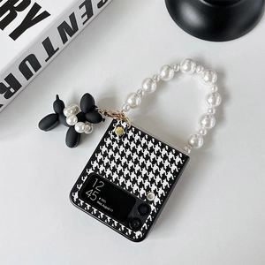 Detail of houndstooth phone case with pearl strap and black balloon dog charm for Z Flip